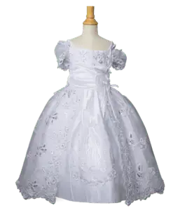 Vestido blanco infantil con mangas cortas abullonadas y detalles bordados religiosos en la falda.